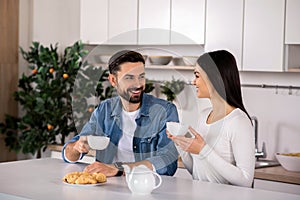Positive young couple drinking tea at home