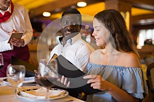 Positive young couple making order at restaurant