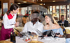 Positive young couple making order at restaurant