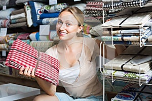 Positive young female customer holding tablecloths