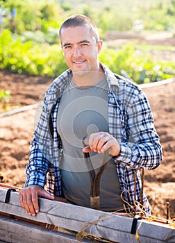 Positive young gardener posing in vegetable garden