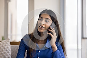 Positive young Indian woman talking on mobile phone