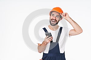Positive young man builder in helmet using mobile phone