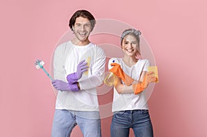 Positive Young Spouses Posing With Cleaning Tools In Hands Over Pink Background