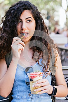 positive young tourist eating fresh fruits in the streets of Barcelona