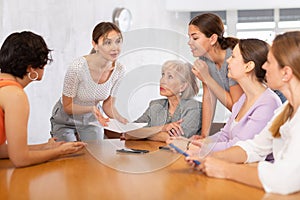 Positive young woman discussing with group of female volunteers