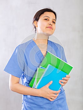 Positive young woman doctor holding medical records