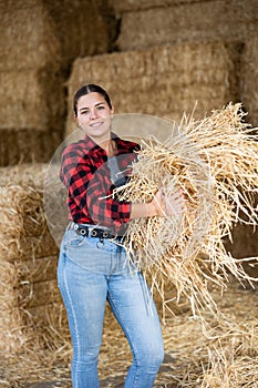 Cheerful woman farmer holding bunch of hay