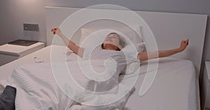 positive young woman stretching her arms, waking, getting up in the morning