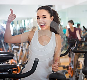 Positive young woman training on exercise bikes