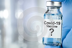 Possible cure concept with a hand in blue medical gloves holding Coronavirus, Covid 19 virus, vaccine vial