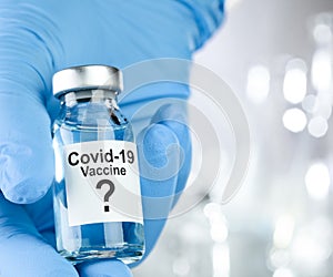 Possible cure concept with a hand in blue medical gloves holding Coronavirus, Covid 19 virus, vaccine vial