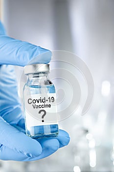 Possible cure concept with a hand in blue medical gloves holding Coronavirus, Covid 19 virus, vaccine vial