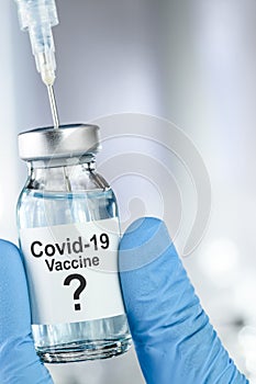 Possible cure concept with a hand in blue medical gloves holding Coronavirus, Covid 19 virus, vaccine vial