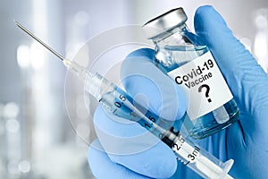 Possible cure with a hand in blue medical gloves holding Coronavirus, Covid 19 virus, vaccine vial photo