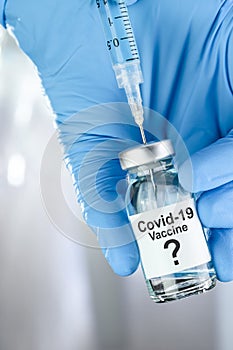 Possible cure with a hand in blue medical gloves holding Coronavirus, Covid 19 virus, vaccine vial