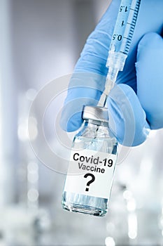 Possible cure with a hand in blue medical gloves holding Coronavirus, Covid 19 virus, vaccine vial
