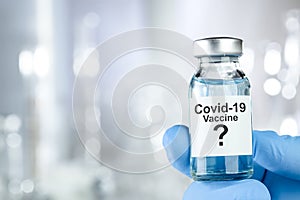 Possible cure with a hand in blue medical gloves holding Coronavirus, Covid 19 virus, vaccine vial