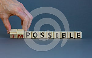 Possible or impossible. Male hand flips wooden cubes and changes the word `impossible` to `possible`. Beautiful grey backgroun