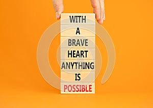 Possible symbol. Concept words With a brave heart anything is possible on wooden blocks on a beautiful orange table orange