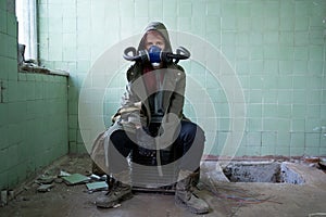 Post apocalyptic survivor in gas mask sitting in a ruined building. Environmental disaster. Environmental pollution