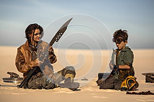 Post Apocalyptic Woman and Boy with Weapons Outdoors in the Wasteland