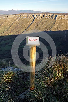 Post with danger sign on mountain cliff