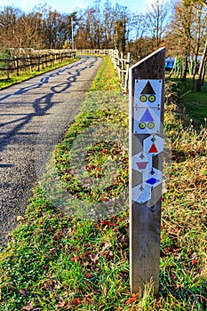 Post with hiking and cycling trail signs on side of a path between wooden fences