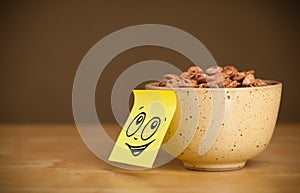 Post-it note with smiley face sticked on cereal bowl