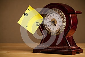 Post-it note with smiley face sticked on a clock