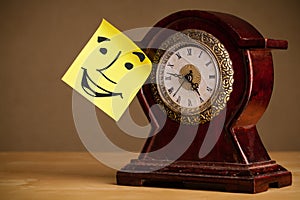 Post-it note with smiley face sticked on a clock