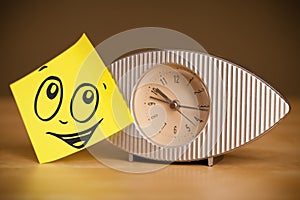 Post-it note with smiley face sticked on clock