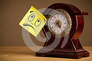 Post-it note with smiley face sticked on clock