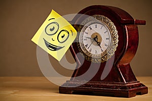 Post-it note with smiley face sticked on clock