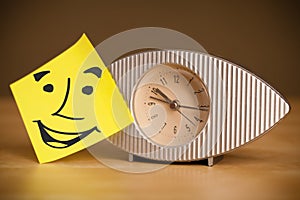 Post-it note with smiley face sticked on a clock