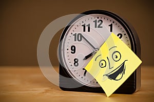 Post-it note with smiley face sticked on clock