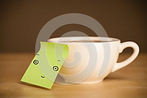 Post-it note with smiley face sticked on a cup