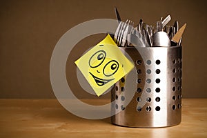 Post-it note with smiley face sticked on cutlery case