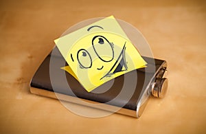 Post-it note with smiley face sticked on hip flask