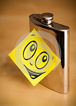 Post-it note with smiley face sticked on hip flask