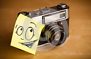 Post-it note with smiley face sticked on photo camera