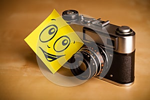 Post-it note with smiley face sticked on photo camera