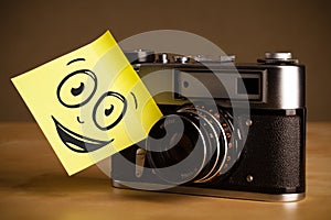 Post-it note with smiley face sticked on photo camera