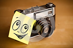 Post-it note with smiley face sticked on photo camera