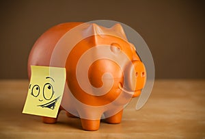 Post-it note with smiley face sticked on a piggy bank