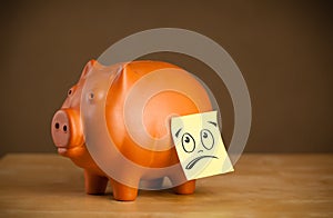 Post-it note with smiley face sticked on piggy bank