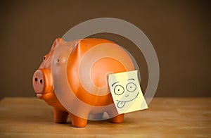 Post-it note with smiley face sticked on a piggy bank