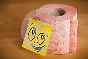 Post-it note with smiley face sticked on toilet paper