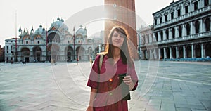 Post-pandemic tourism. Happy young attractive dark haired Caucasian tourist woman walks to camera smiling at Venice