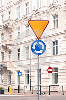 Post with Roundabout and Yield road signs on city street